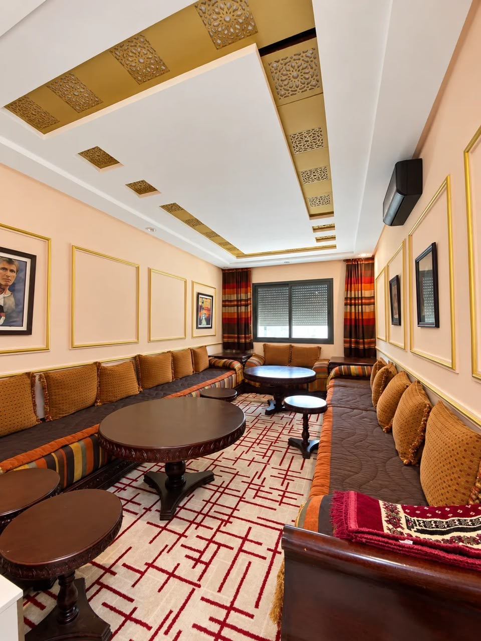 Amber and gold Moroccan salon with carved tables and decorative ceiling