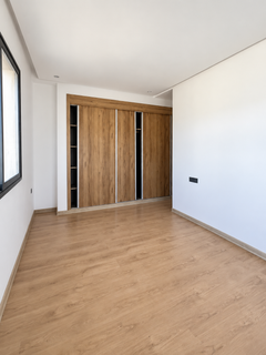 Empty bedroom with window and long built-in wardrobe in the Founty apartment