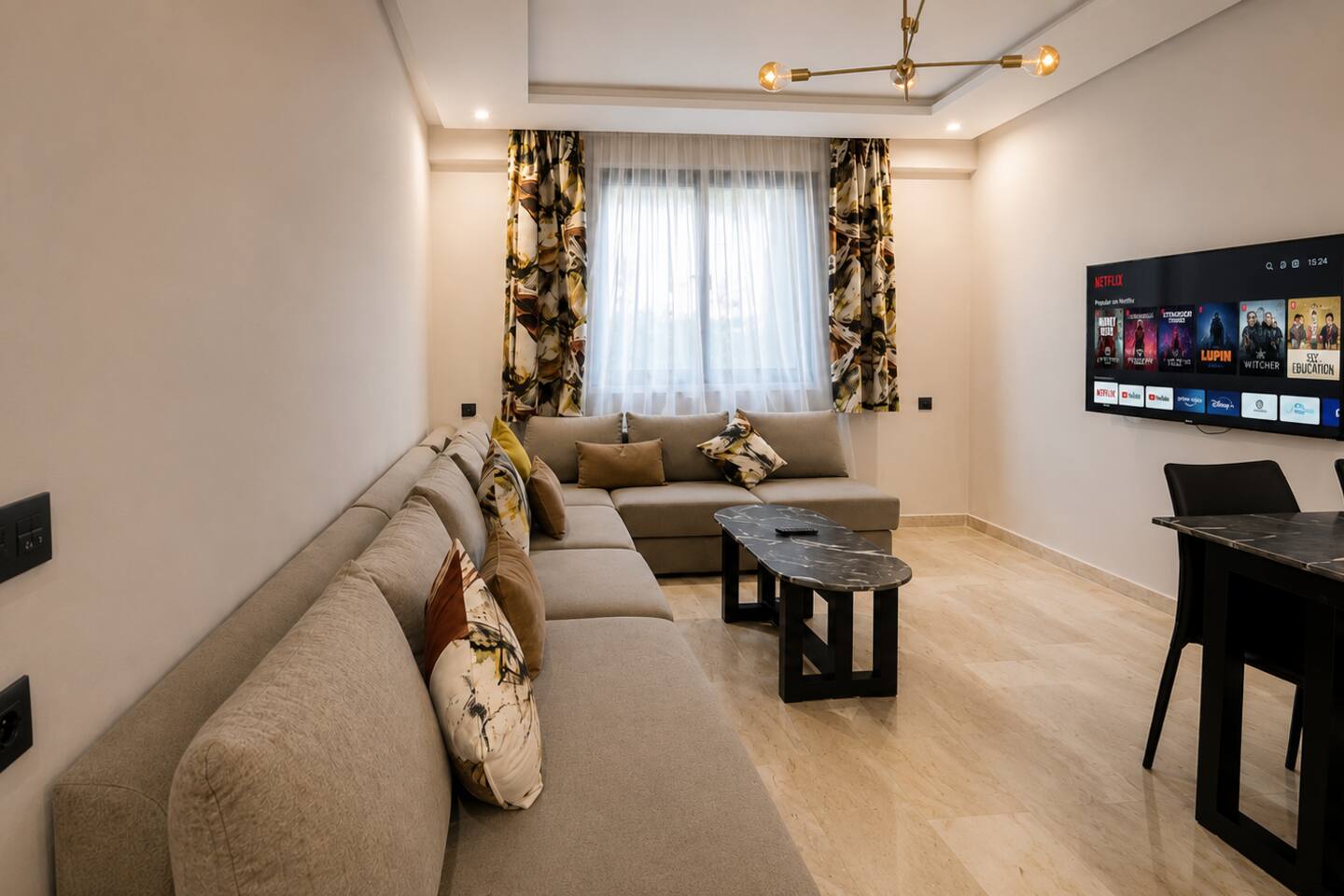 Living room with sofa, dining table and wall-mounted smart TV in Agadir Bay.