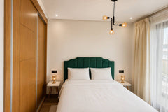 Main bedroom with balcony access and green upholstered bed in Agadir Bay.
