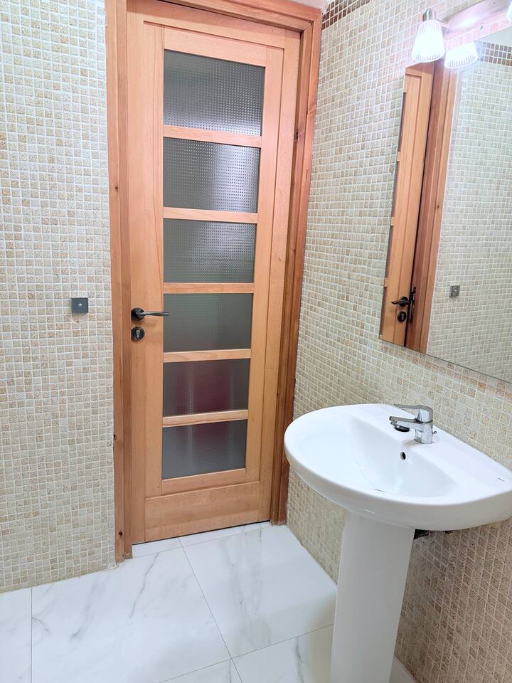 Bathroom with basin, toilet and tiled walls in the central Agadir apartment.