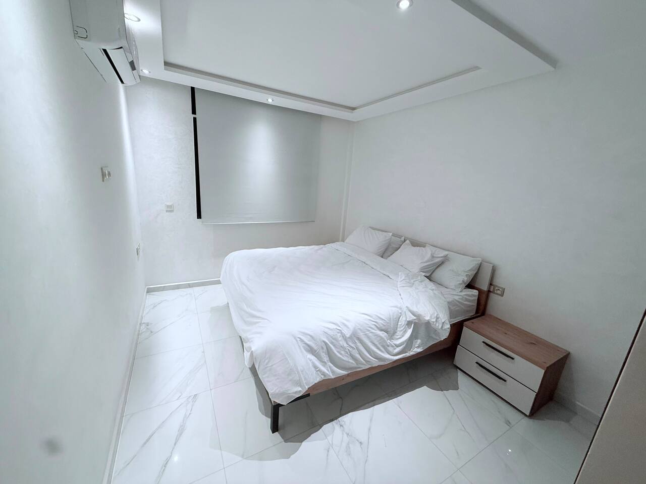 Double bedroom with neutral bedding in the central Agadir apartment.