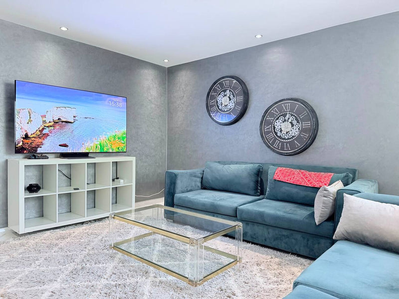 Living room with blue corner sofa and smart TV in the central Agadir apartment.