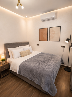 Comfortable main bedroom in DHAJIA Haut Founty, Agadir apartment with soft bedding, AC, warm lighting and modern décor.