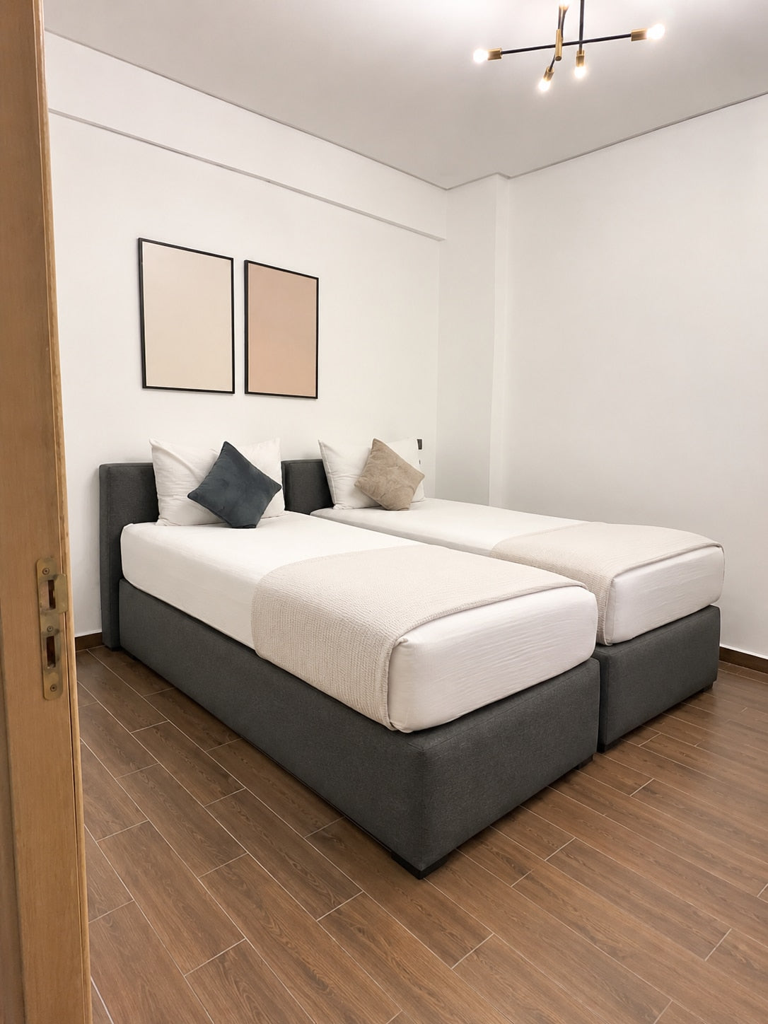 Second bedroom with two single beds and neutral décor in the Haut Founty apartment.