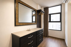 Bedroom storage area with dresser, large mirror and natural light in Haut Founty.