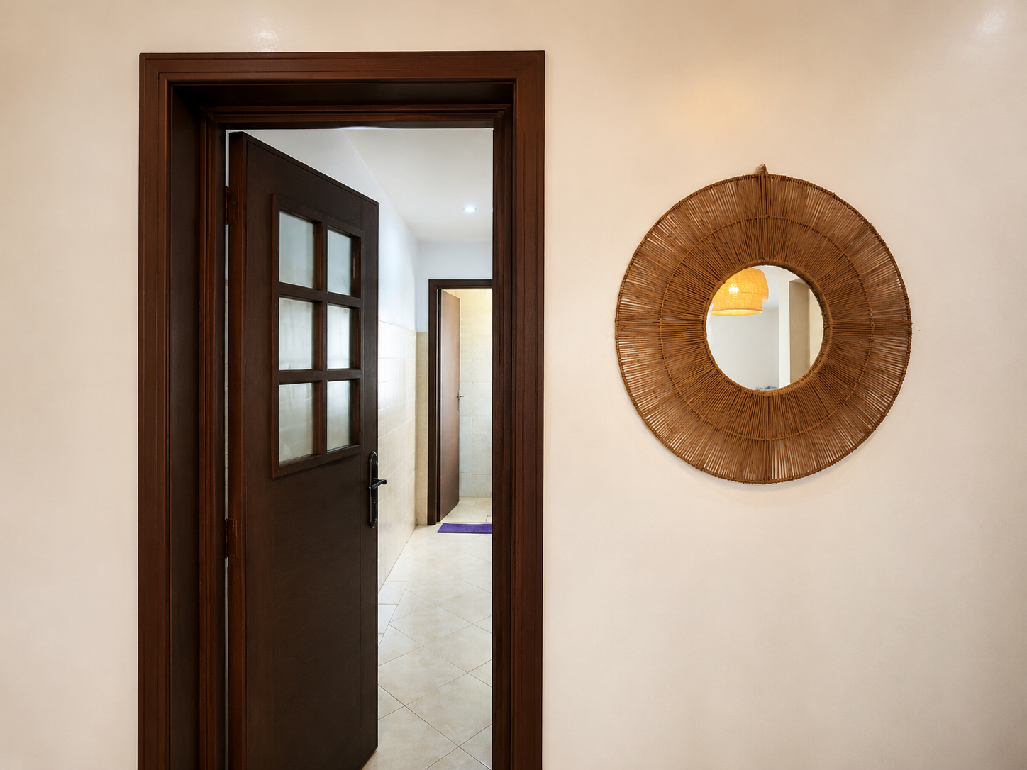 Apartment hallway with round mirror and wood-framed doors in Haut Founty.