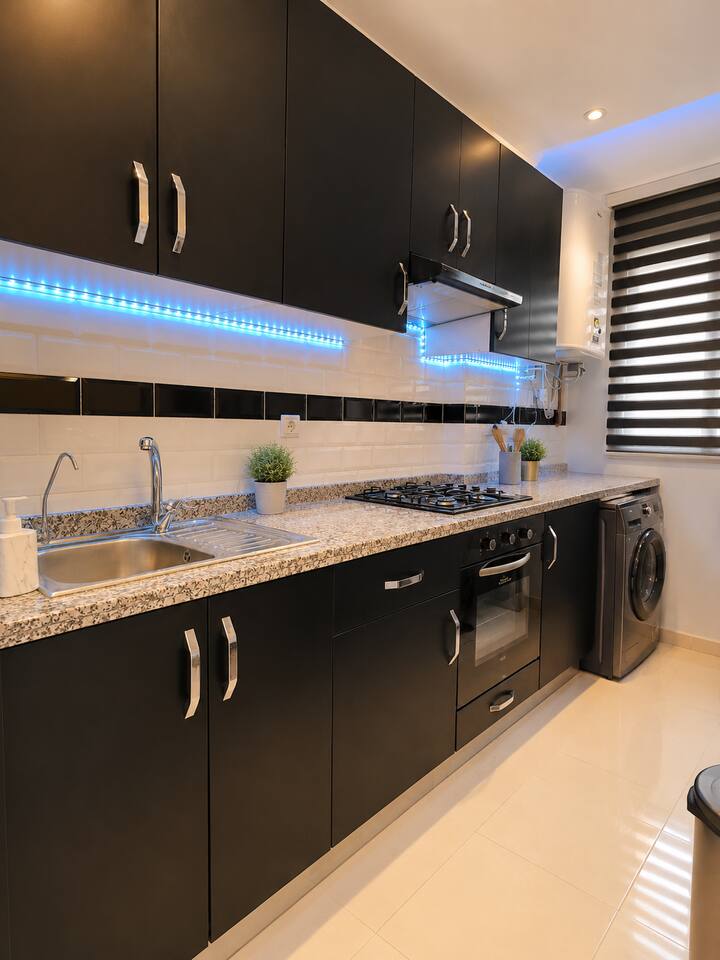 Black galley kitchen with worktops and washing machine in Hay Mohammadi.