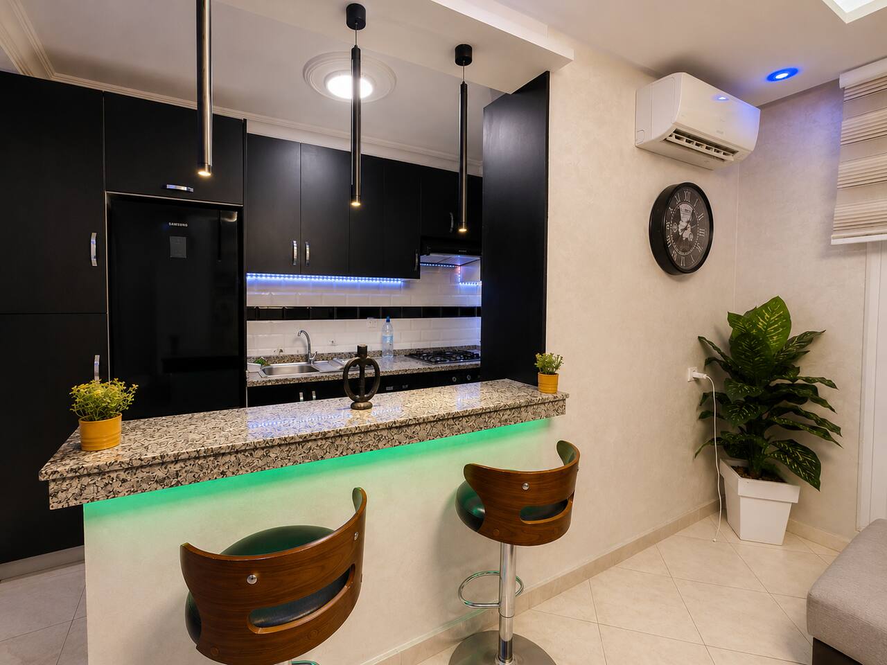 Black kitchen and illuminated breakfast bar in the Hay Mohammadi apartment.