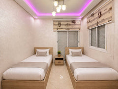 Twin bedroom with two single beds and purple ceiling lighting in Hay Mohammadi.