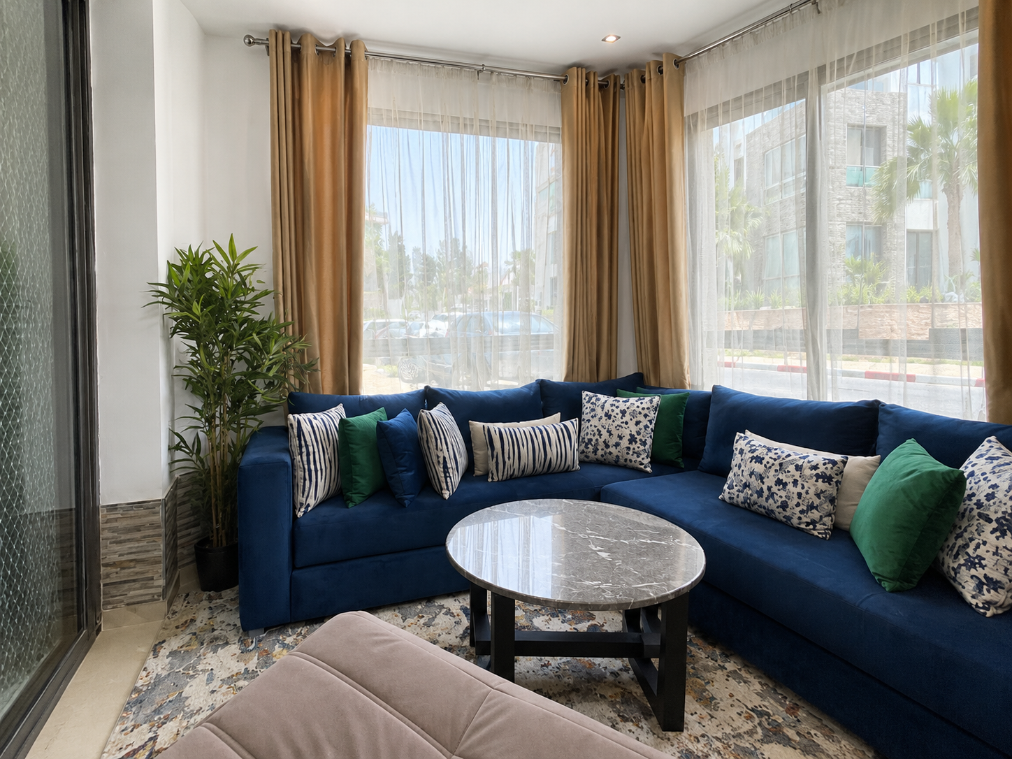 Bright living room with blue corner sofa and marble table in the Hivernage apartment.