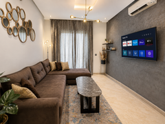Living room with sofa and wall-mounted smart TV in the Hivernage apartment.