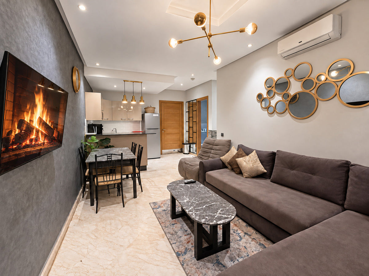 Living room with grey corner sofa, television and dining area at the Hivernage Agadir Bay apartment