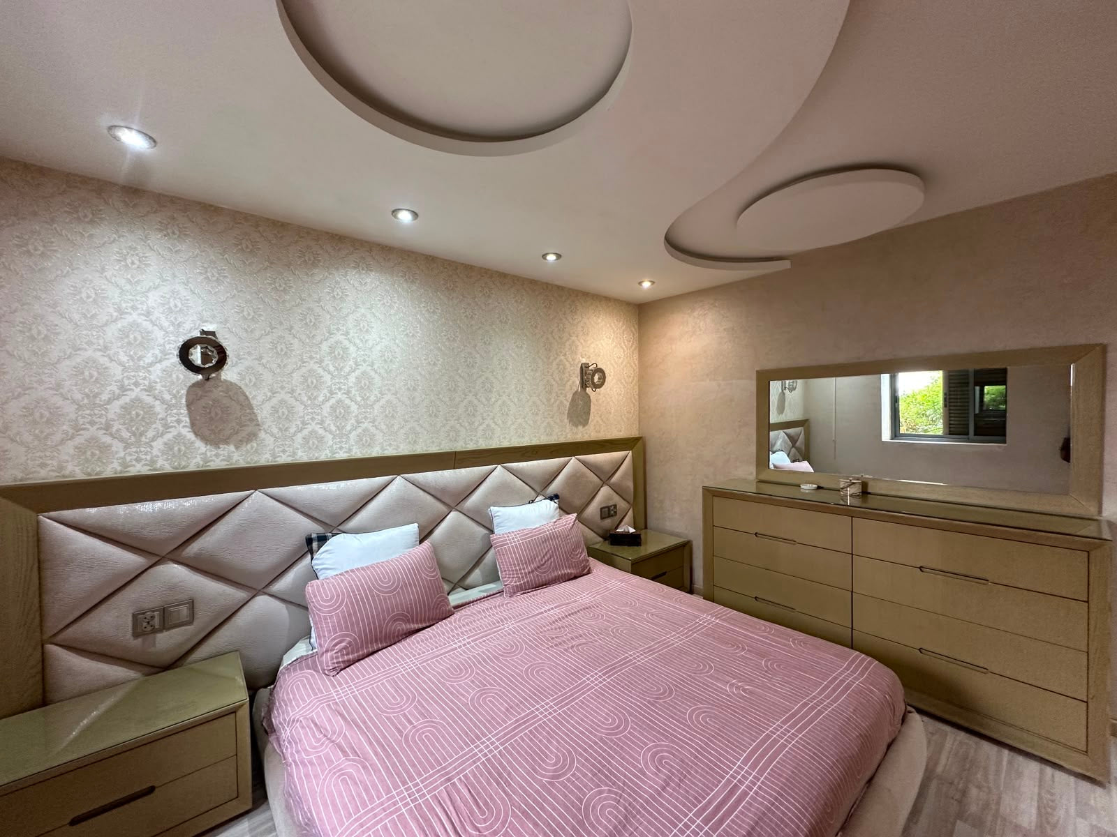 Main double bedroom with upholstered headboard at the Iken Gardens apartment in Agadir Bay.