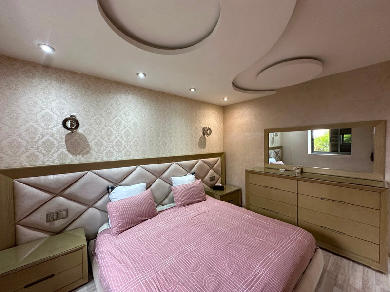 Main double bedroom with upholstered headboard at the Iken Gardens apartment in Agadir Bay.