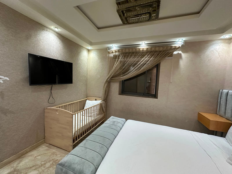 Second double bedroom with Smart TV and baby cot at the Iken Gardens apartment.