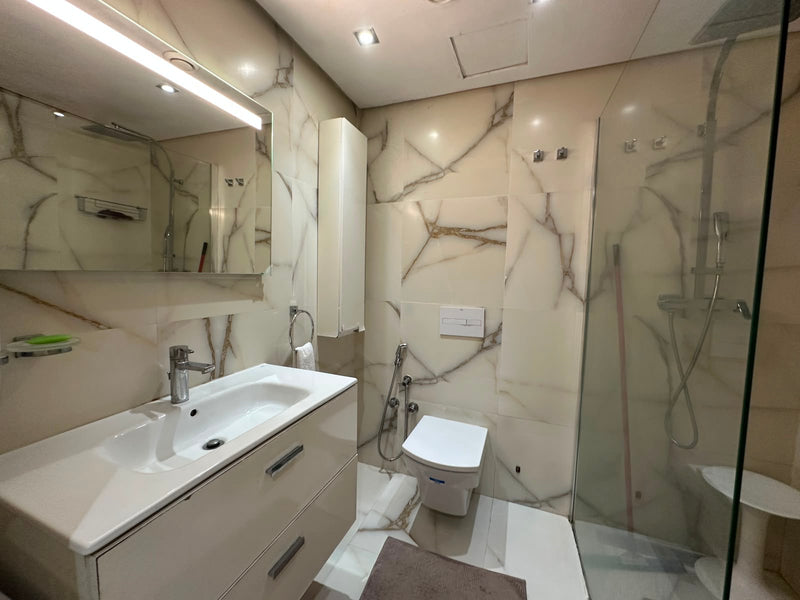 Walk-in rainfall shower and illuminated mirror in the Iken Gardens apartment bathroom.
