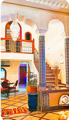Traditional Moroccan riad atrium with tiled columns and stairs