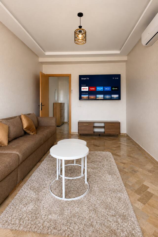 Living room seating facing a wall-mounted smart TV in the premium apartment.