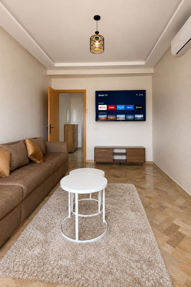 Living room with long sofa, coffee table and smart TV near Agadir Bay.