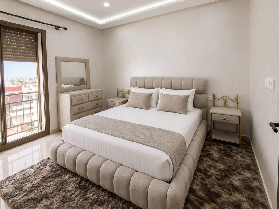 Main bedroom with upholstered double bed and balcony access in the premium apartment near Agadir Bay.