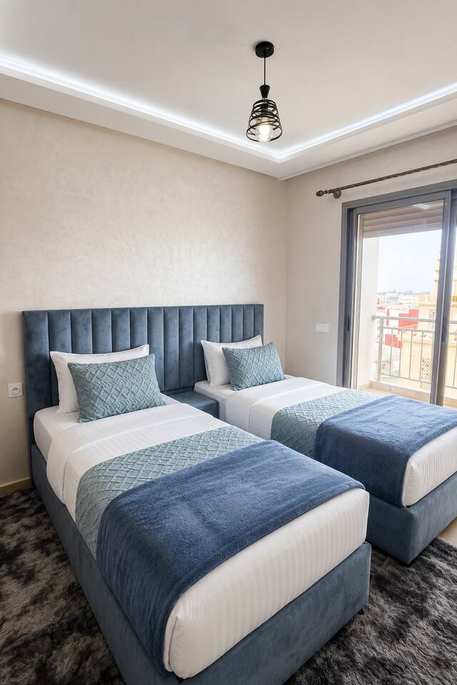 Twin bedroom with two single beds beside a bright window near Agadir Bay.
