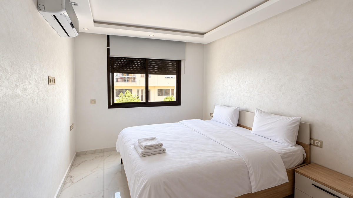 Double bedroom with white linens at the Central Agadir holiday apartment near the beach and souk