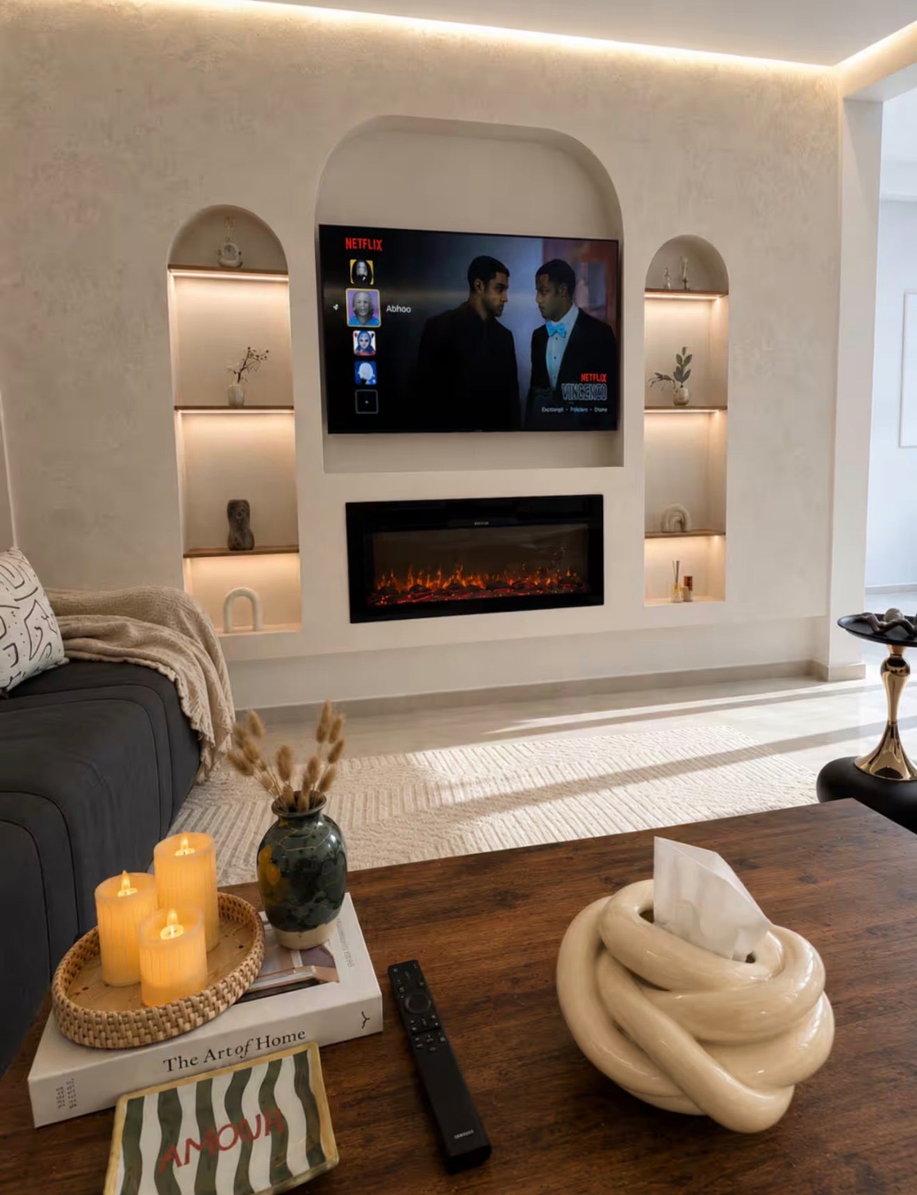 Feature wall lounge in DHAJIA Tilila, Agadir apartment with TV, warm lighting and refined interior styling.