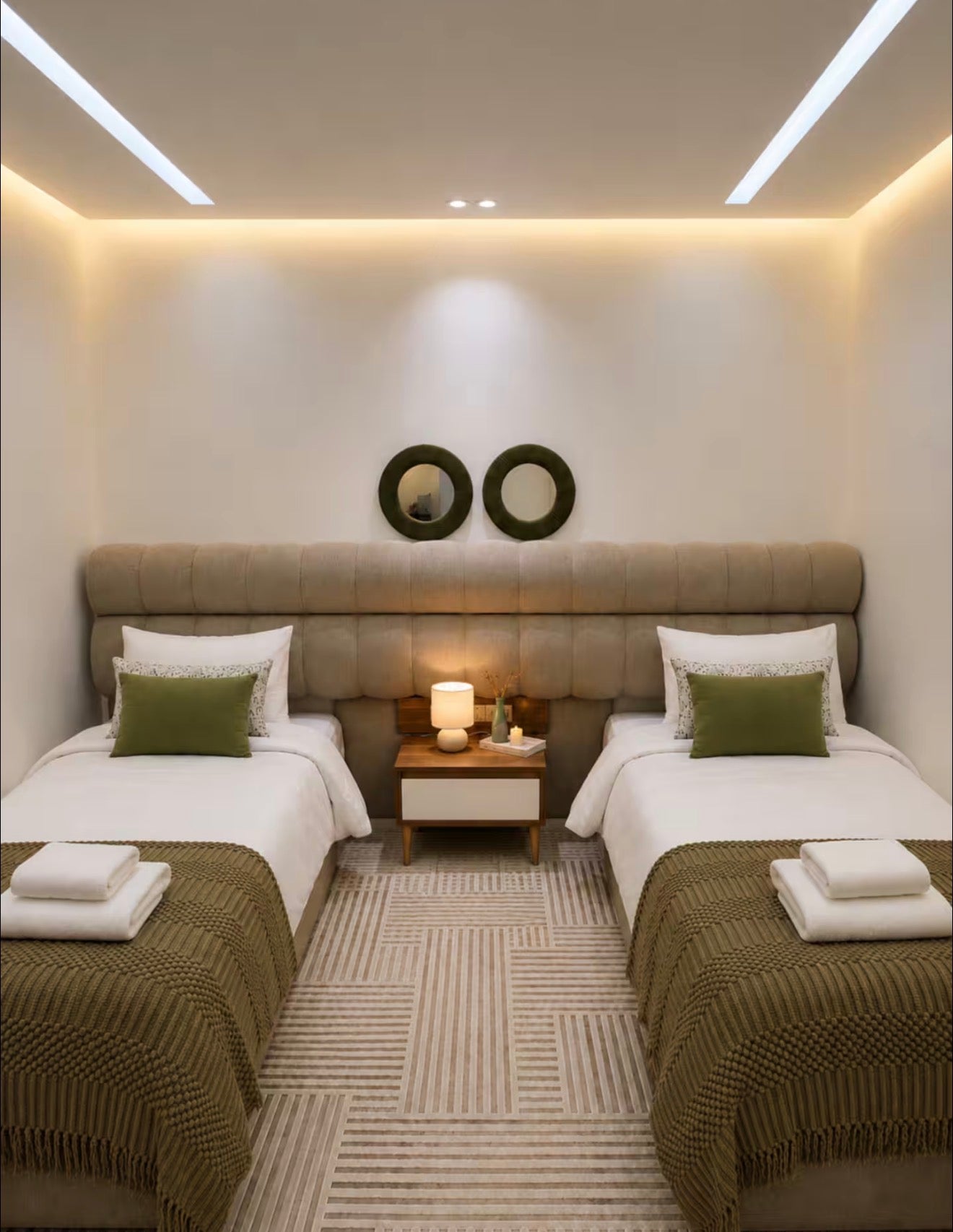 Twin bedroom in DHAJIA Tilila, Agadir apartment with soft bedding, warm lighting and modern décor.