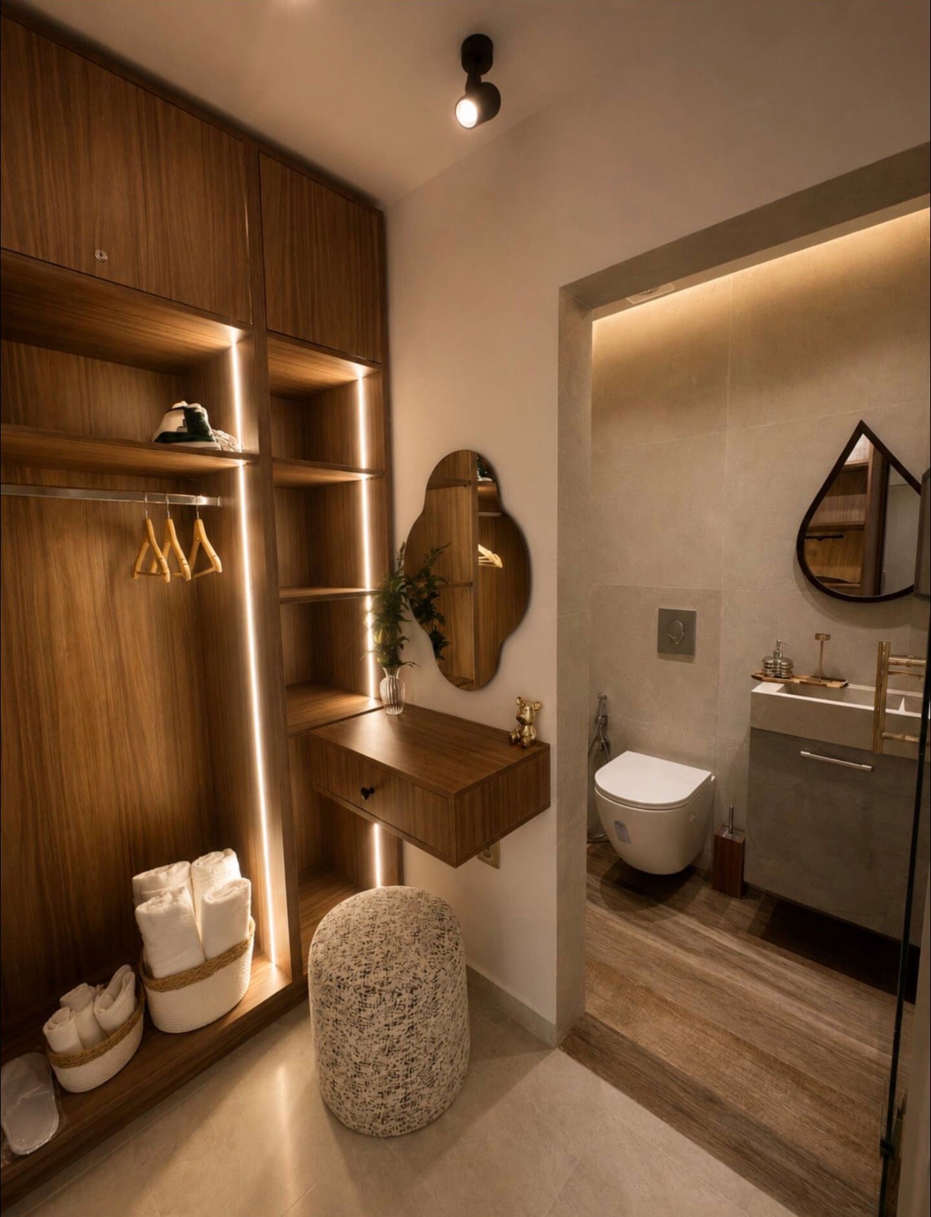Walk-in wardrobe and dressing storage area in DHAJIA Tilila, Agadir apartment with warm lighting and modern bathroom access.