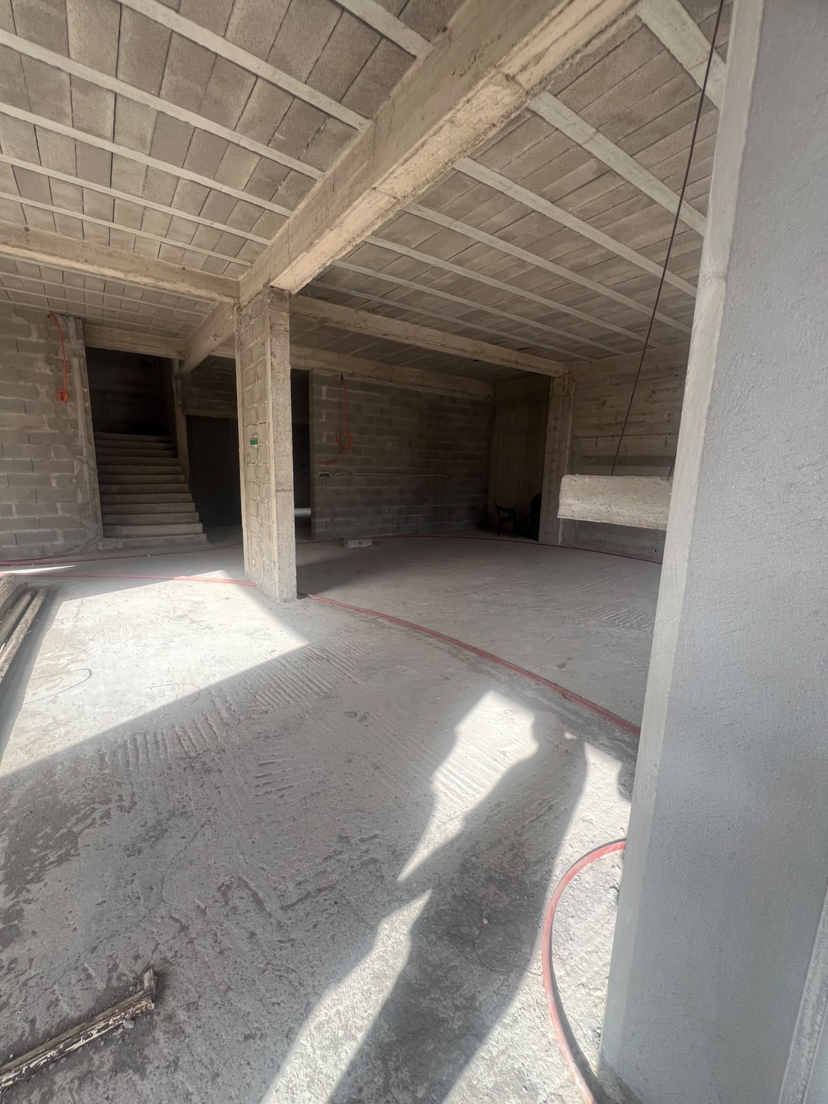 Unfinished modern villa interior with exposed concrete beams, masonry walls and staircase