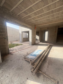 Open interior of the unfinished villa with masonry walls and large courtyard openings