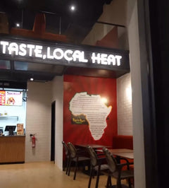 Illuminated slogan and red feature wall inside Peri Peri Grill, Agadir Bay